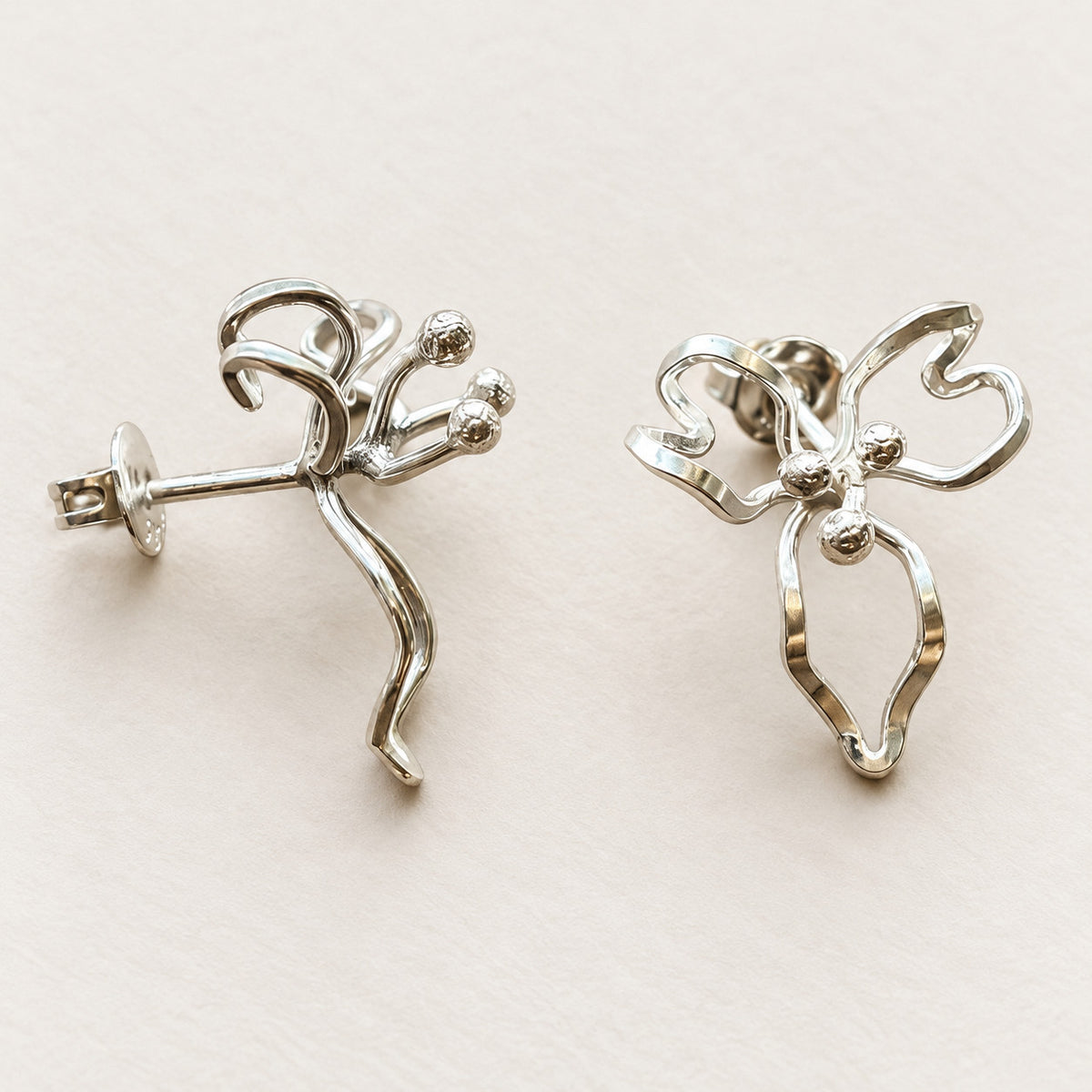 Juniblommans stiftörhängen i silver med stift och fjärilslås synliga.